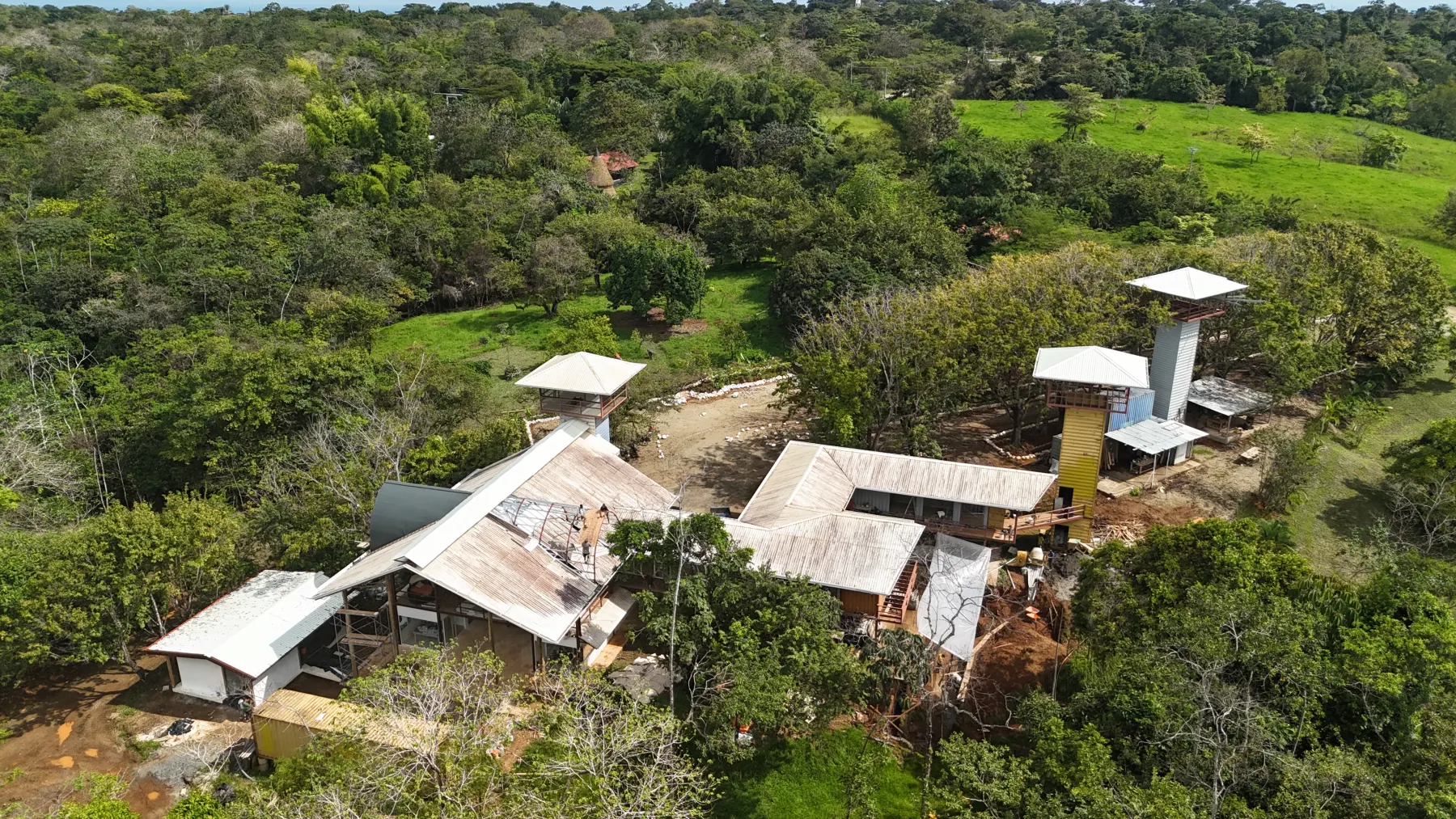 Drone photo of the Elevate buildings under construction, with container towers and metal roofs among the trees